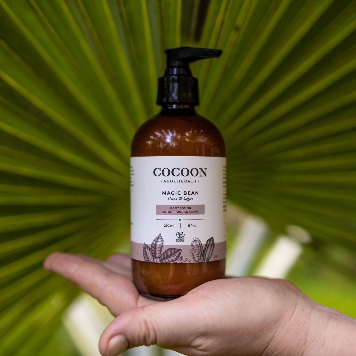 Cocoon Apothecary bottle held in a hand with a green leafy background