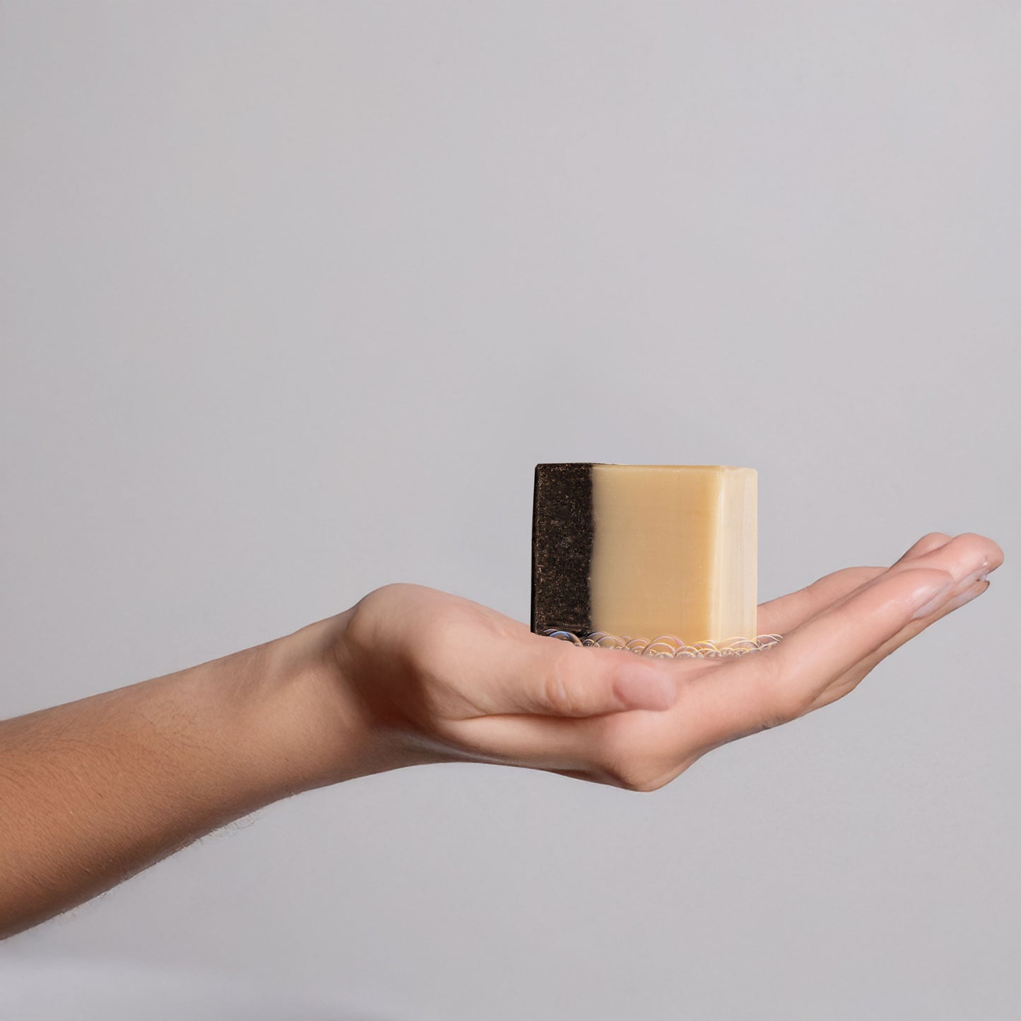 Hand holding a bar of soap with gentle suds