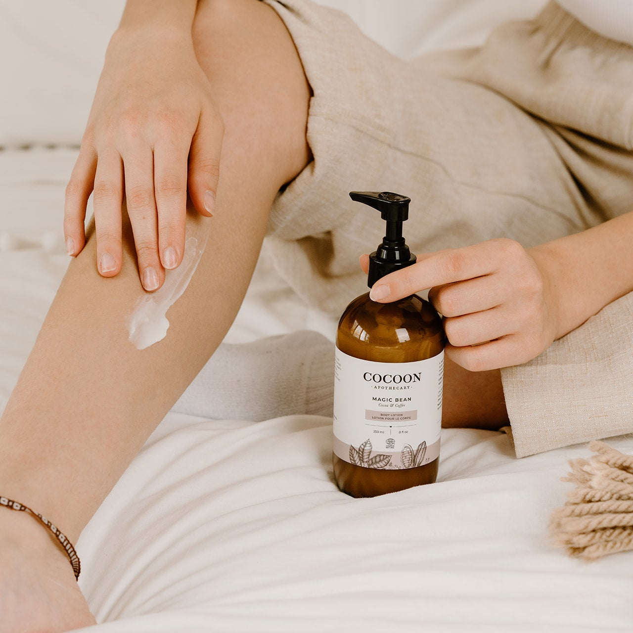 Person applying lotion to their arm with a bottle of Cocoon Magic Bear Lotion nearby.