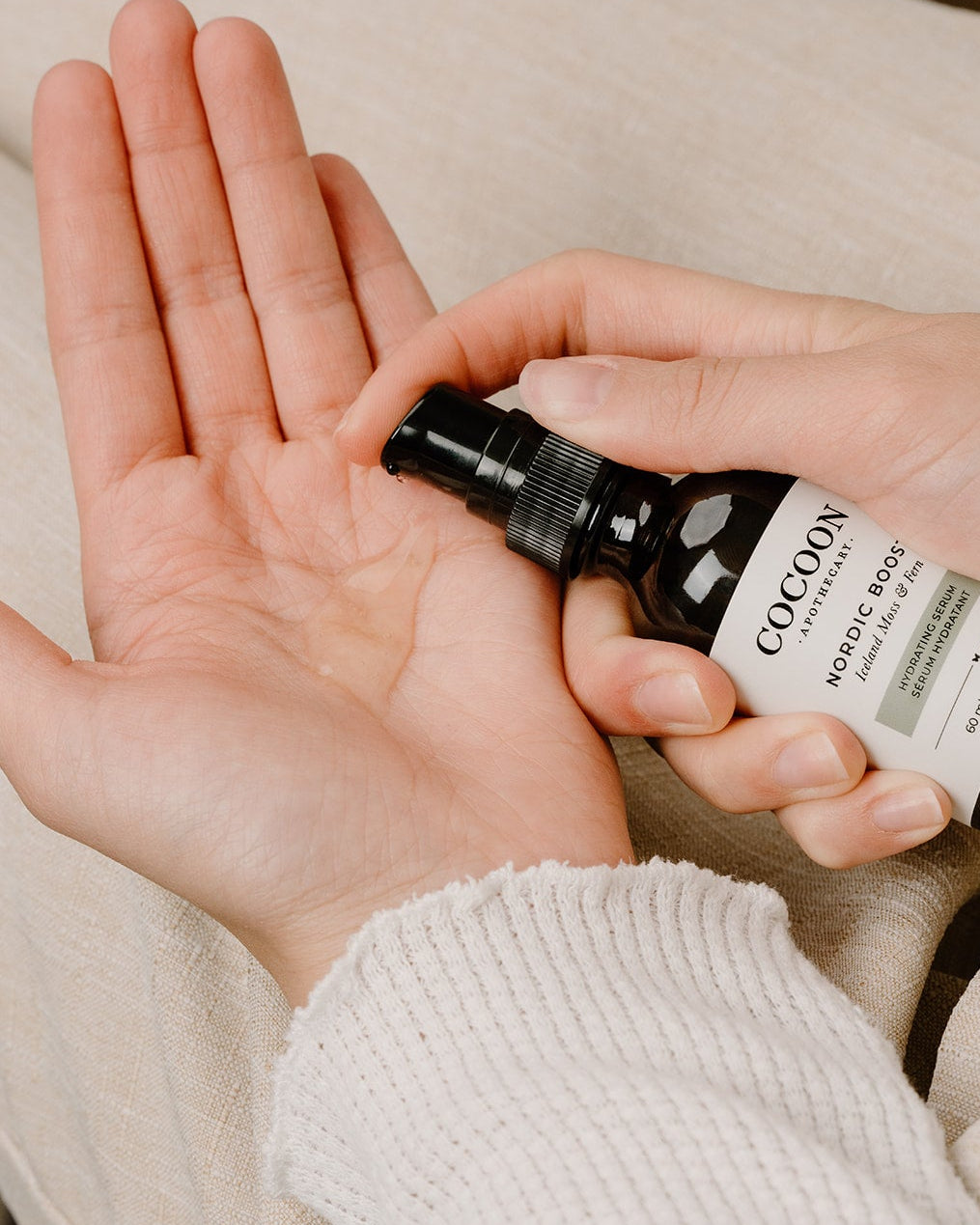 Person holding a bottle of Cocoon body oil in their palm