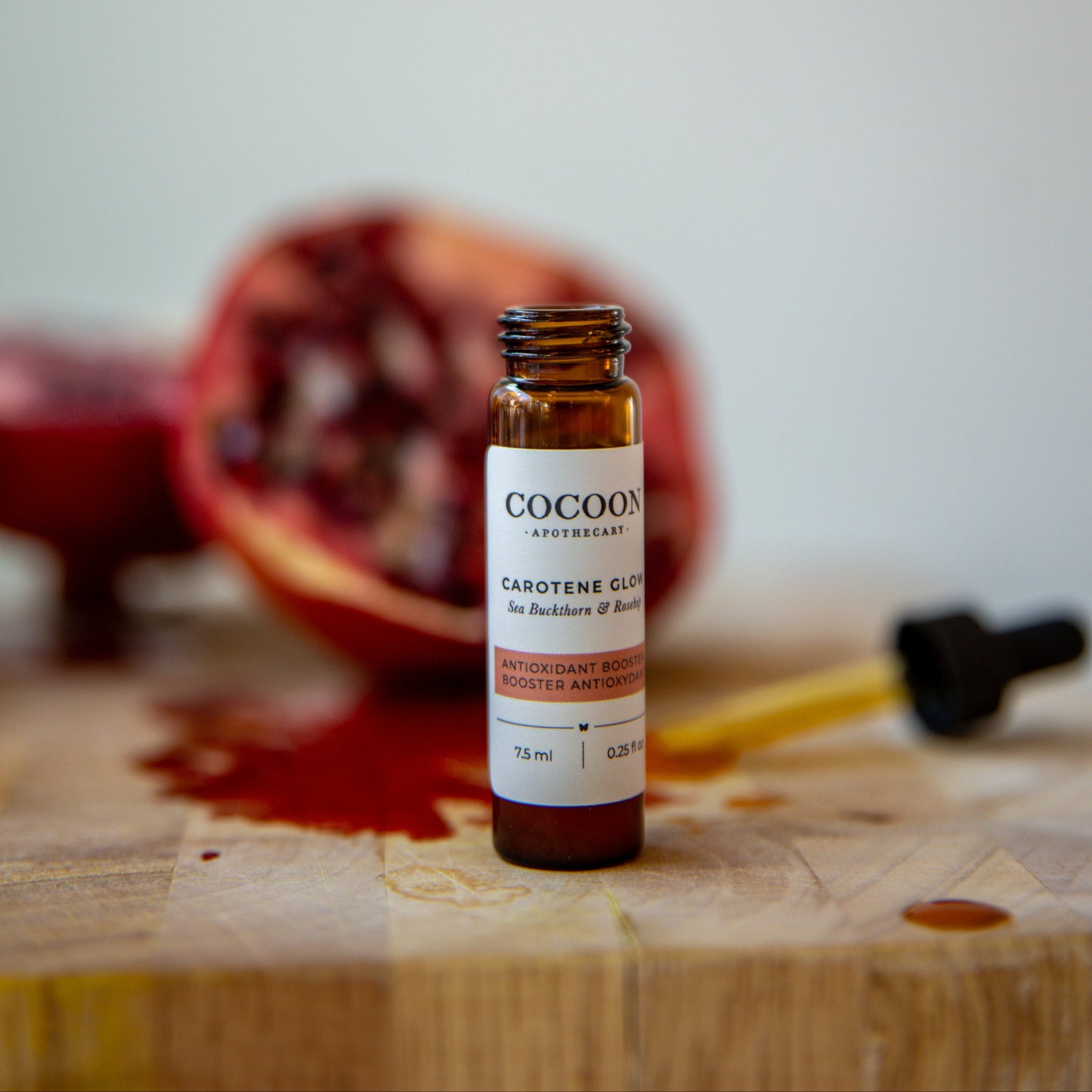 Small bottleoof Carotene Glow Antioxidant Booster on a wooden surface with a pomegranate in the background