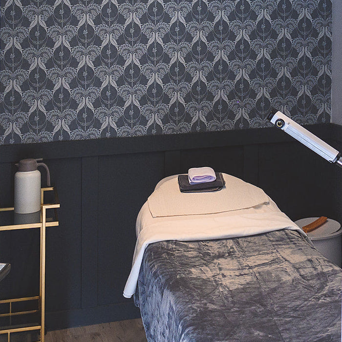 Treatment room with a bed and wall decor, featuring a sign that reads 'Rowan Tree Room'.