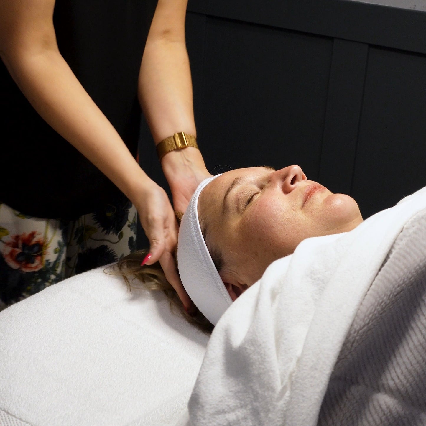 Person receiving a facial treatment with a professional in a clinical setting.