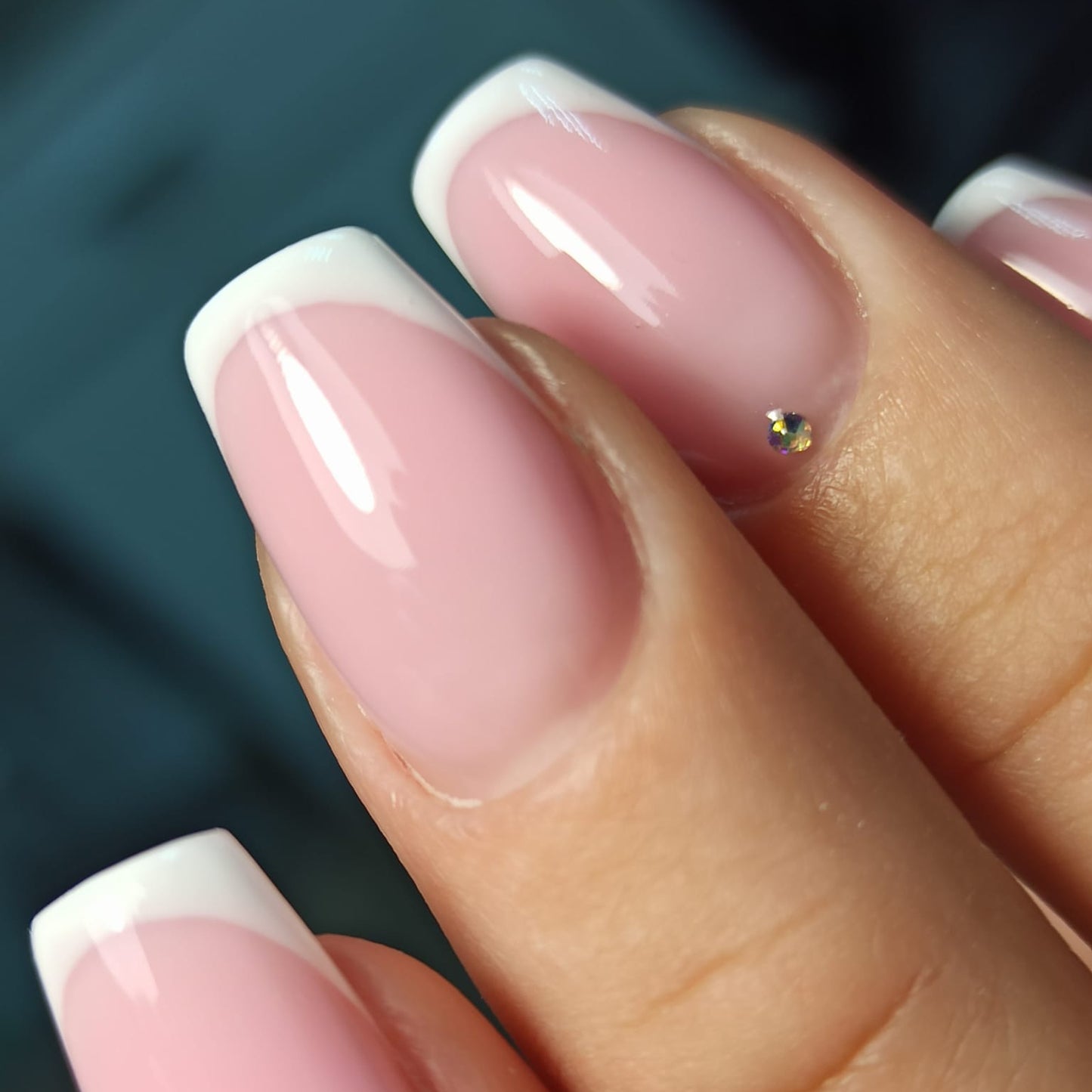 Close-up of a hand with pink and white nail polish on a blurred background