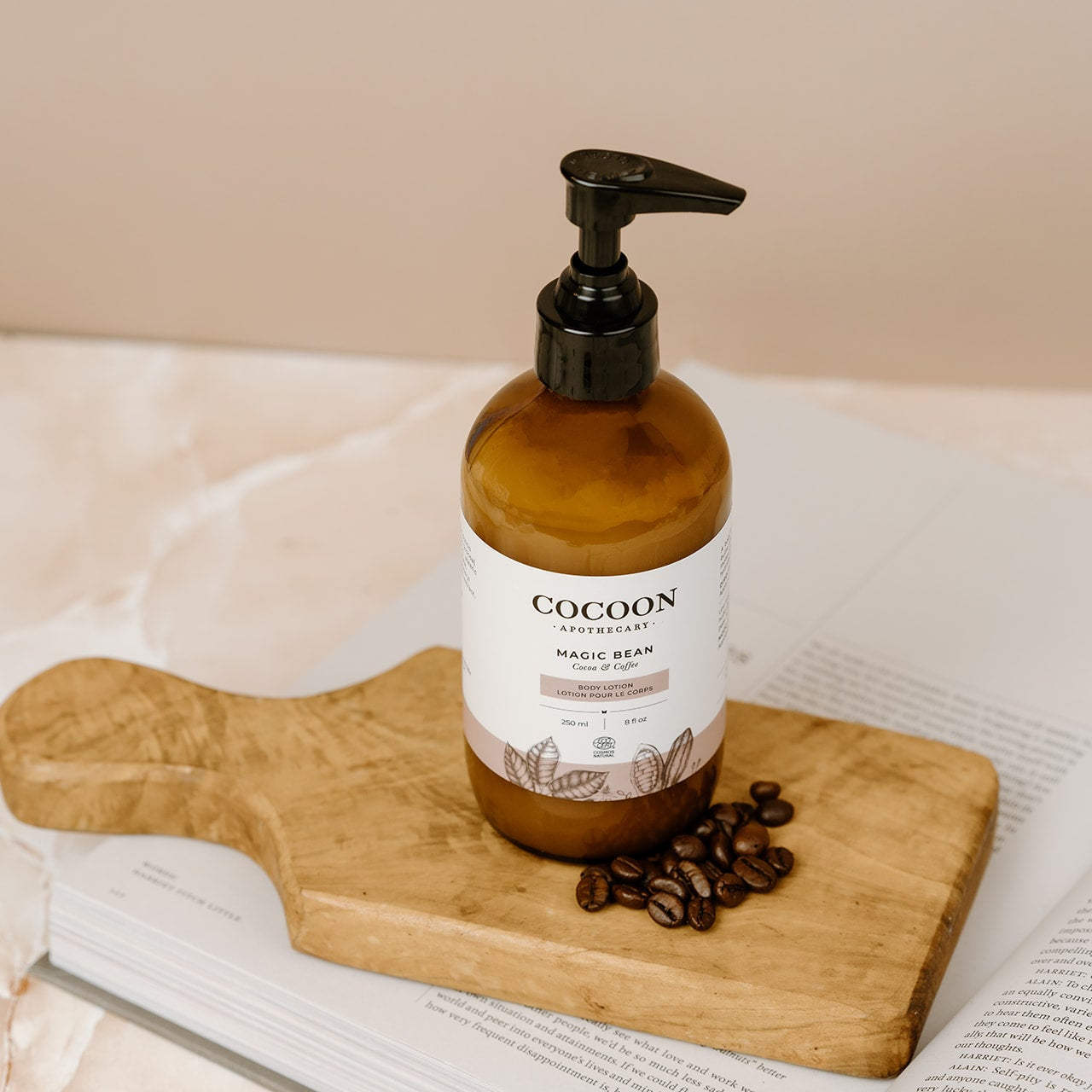 Cocoon bottle on a wooden board with coffee beans on an open book