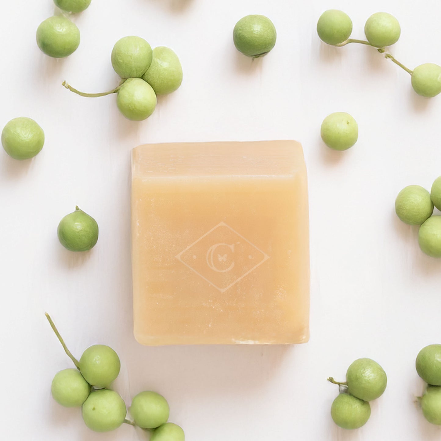 Bar of soap with a brand logo surrounded by litsae cubeba berries on a white background