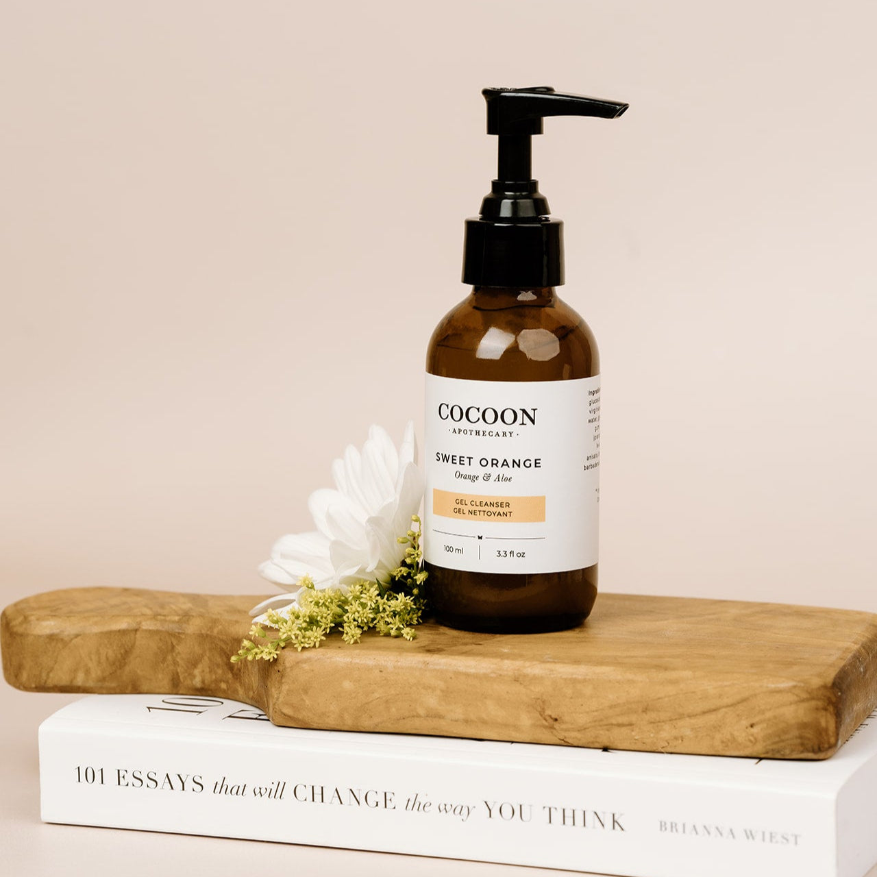 Cocoon skincare bottle on a wooden board with a white flower