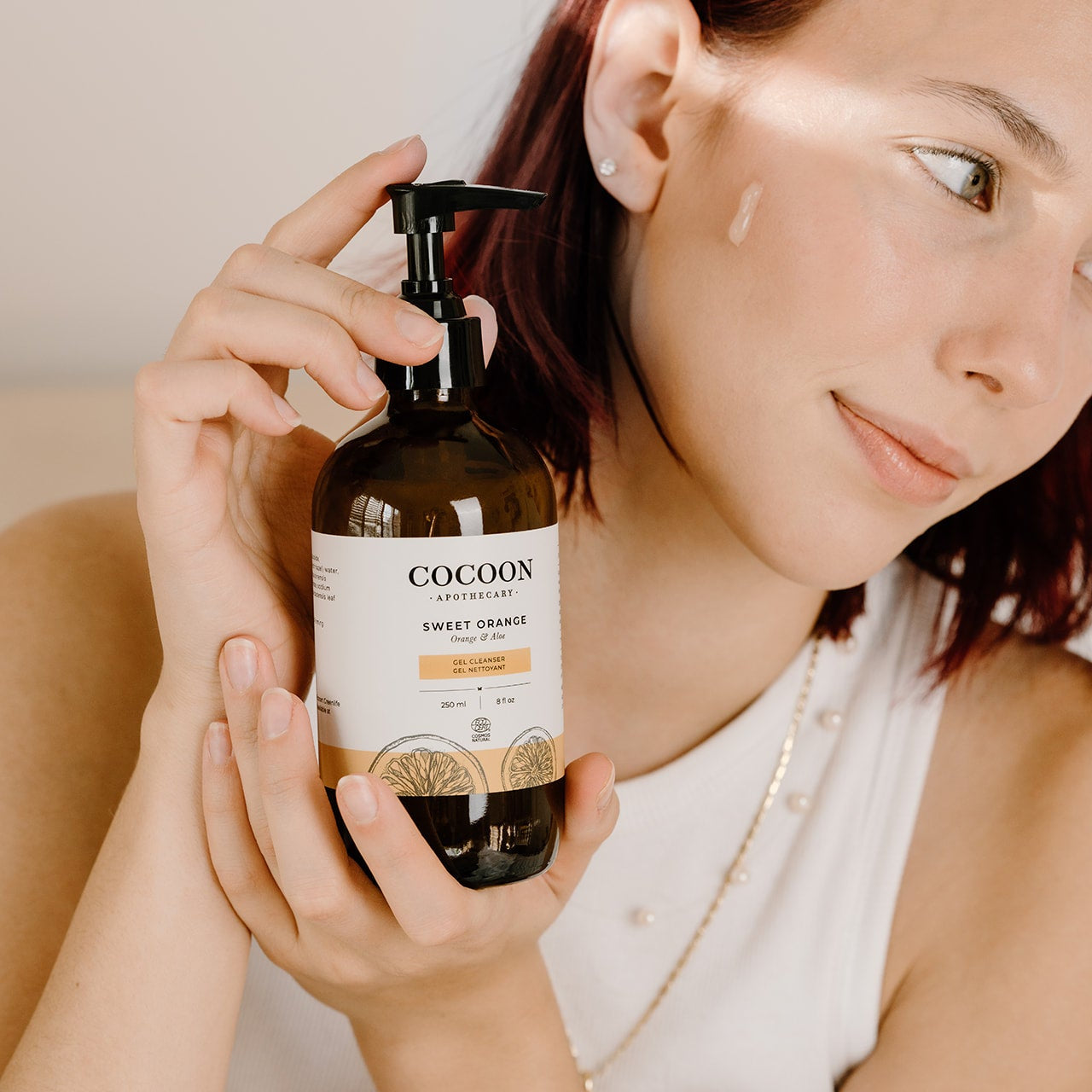 Person holding a bottle of Cocoon Sweet Orange product showing the gentle aloe based gel cleanser