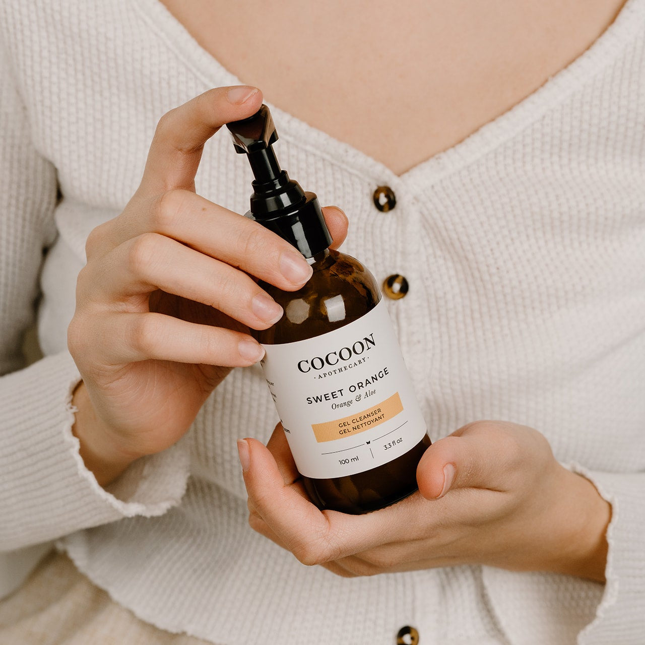 Person holding a bottle of Cocoon Sweet Orange body cleanser.