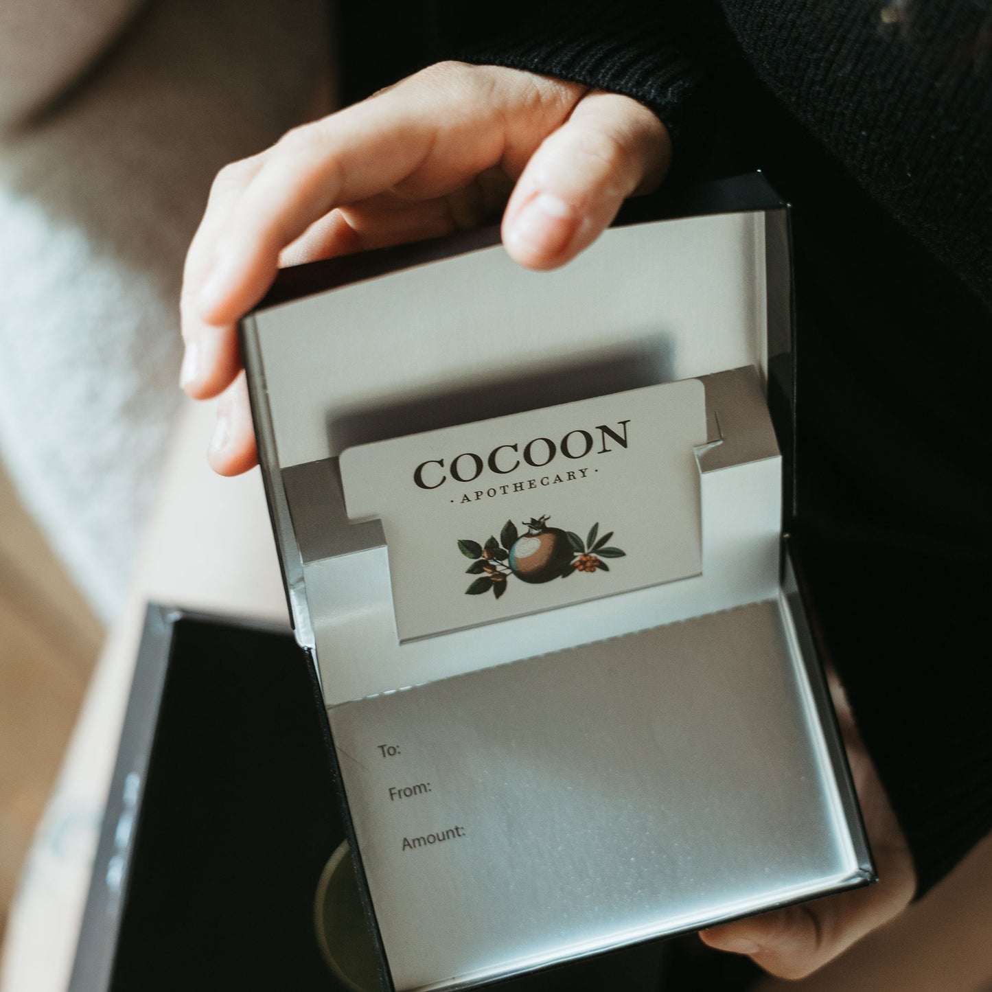 Person holding a gift box with Cocoon gift card