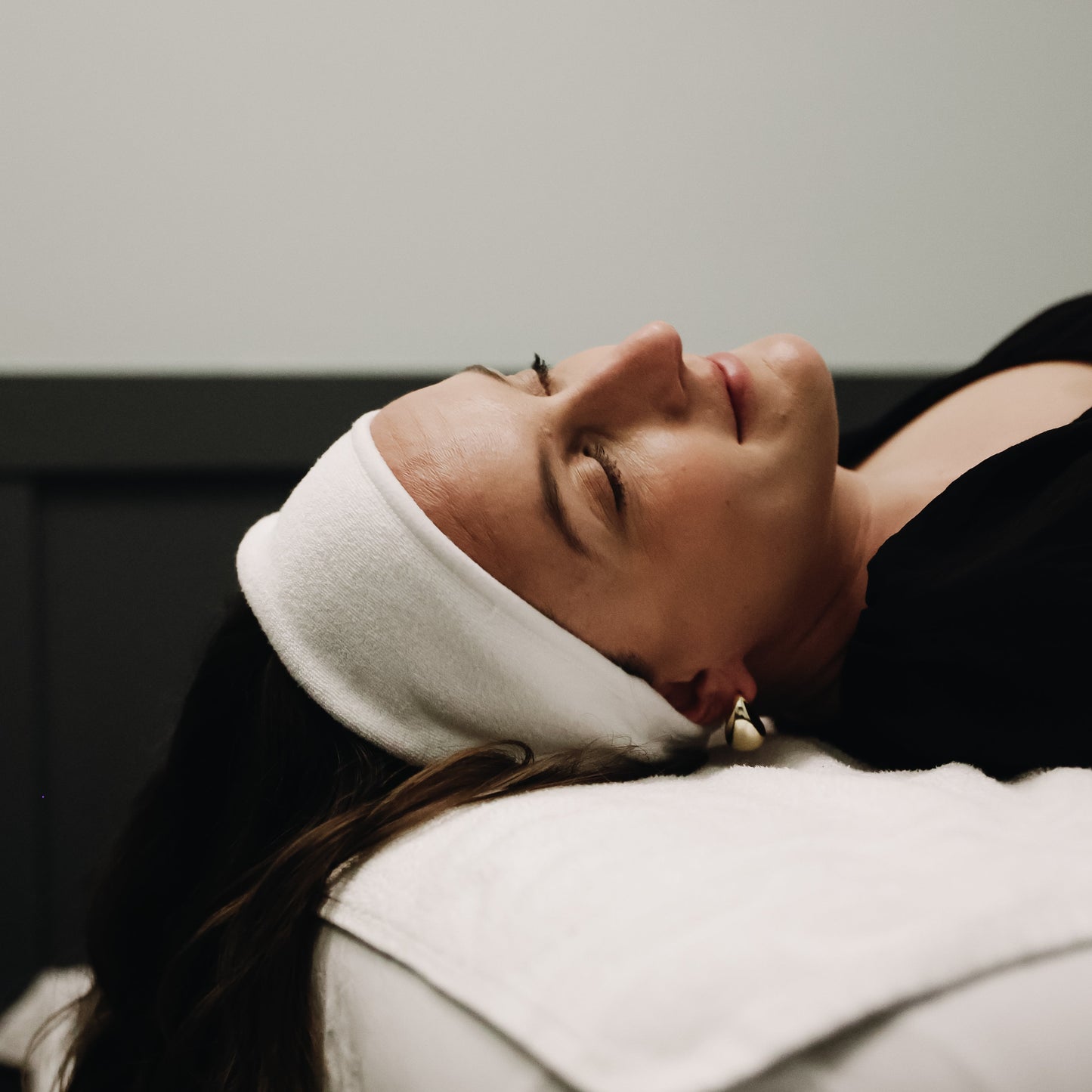 Woman lying down with a white headband on a neutral background