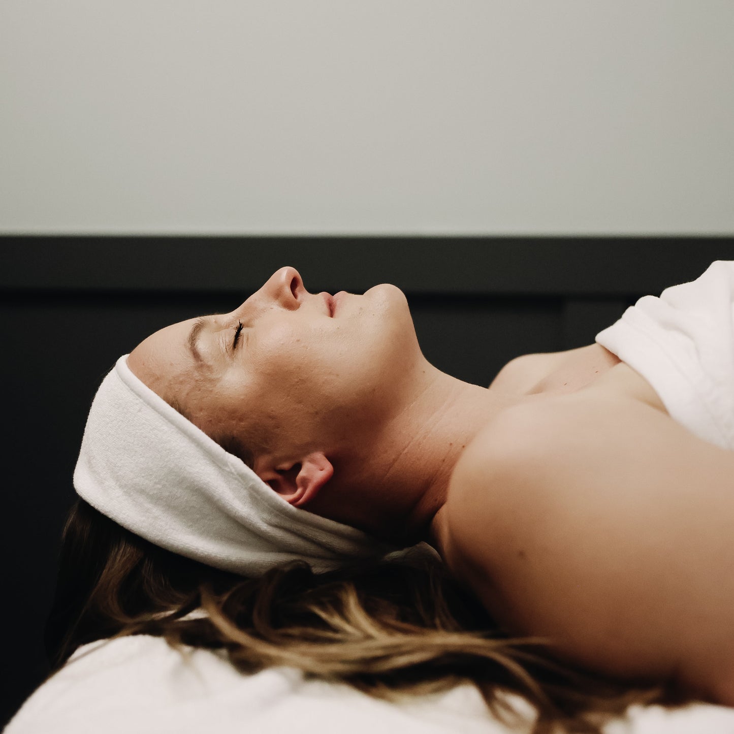 Woman receiving a facial with a towel on her head in a spa setting.