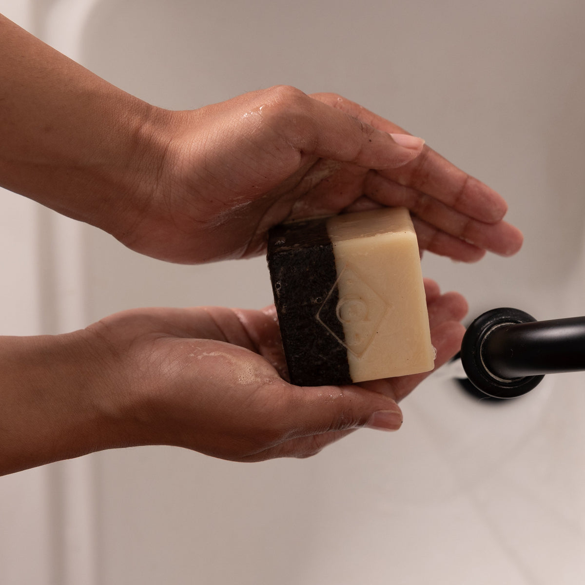 coffee scrub soap being held over sink