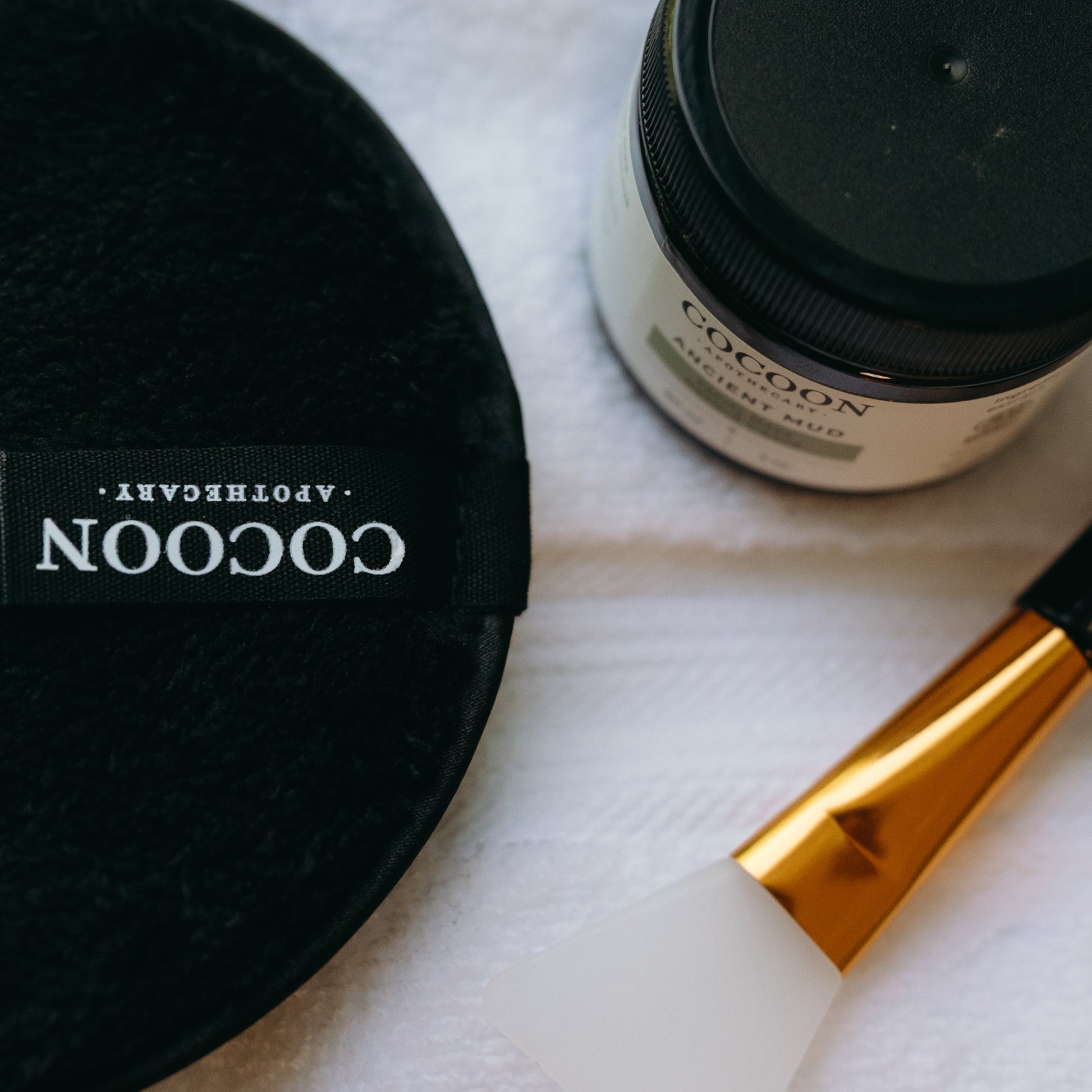 Cocoon Apothecary Ancient mud, removal sponge, mask brush on a white surface
