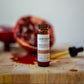 Small bottleoof Carotene Glow Antioxidant Booster on a wooden surface with a pomegranate in the background