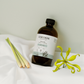 Cocoon product bottle with lemongrass and ylang flower on a white surface