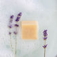 Bar of soap with lavender flowers on a textured surface