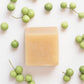 Bar of soap with a brand logo surrounded by litsae cubeba berries on a white background