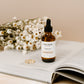 Cocoon Argan Oil bottle on an open book with flowers in the background