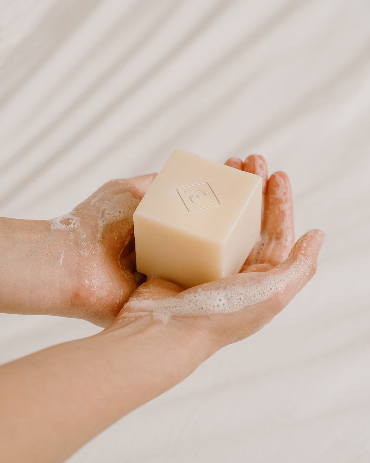 Hand holding a bar of soap with a light background