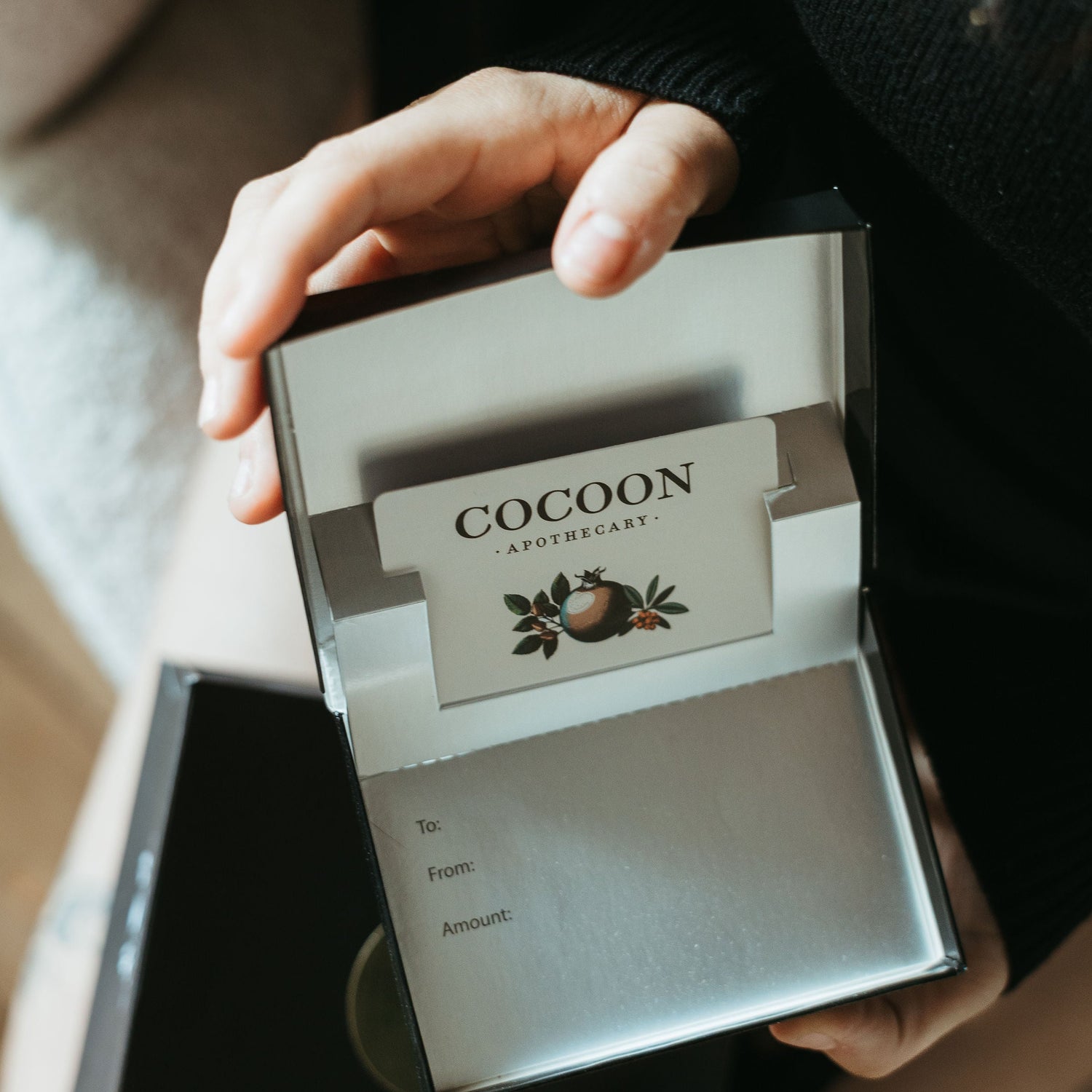 Person holding a gift box with Cocoon gift card