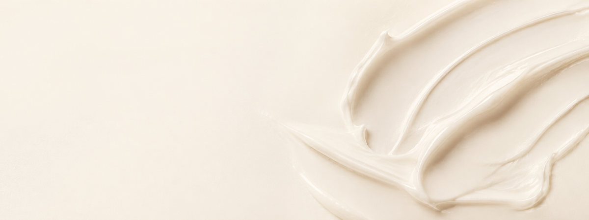Creamy off-white cosmetic texture swatch with smooth sweeping strokes on a light neutral background.