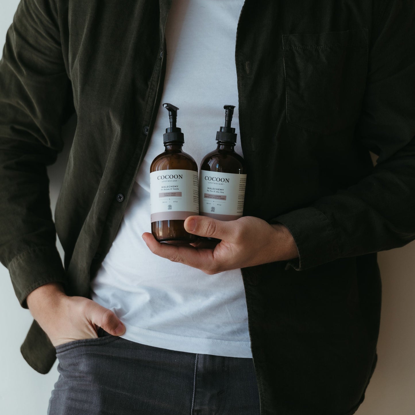 Person holding two bottles of a product with a plain background