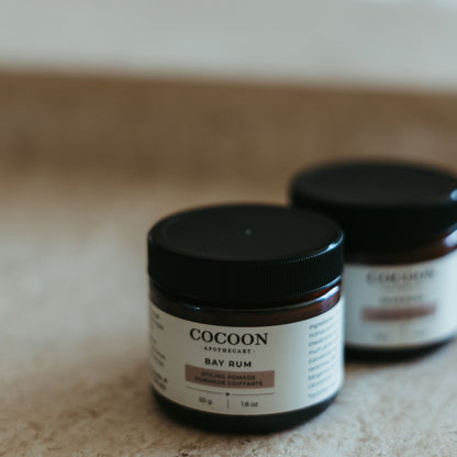 Two jars of Cocoon Bay Rum on a textured surface with a blurred background