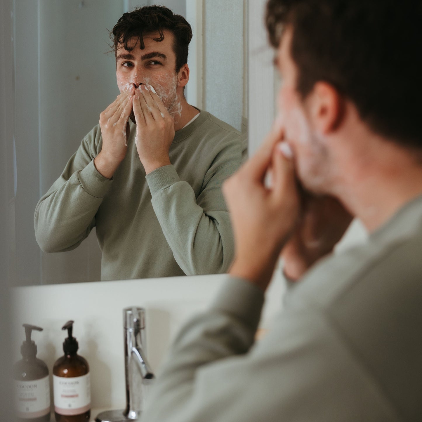 Man applying facial product in front of a mirror