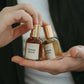 Two small perfume bottles labeled 'Terre Noir' and 'Men's Boss' held in a hand.