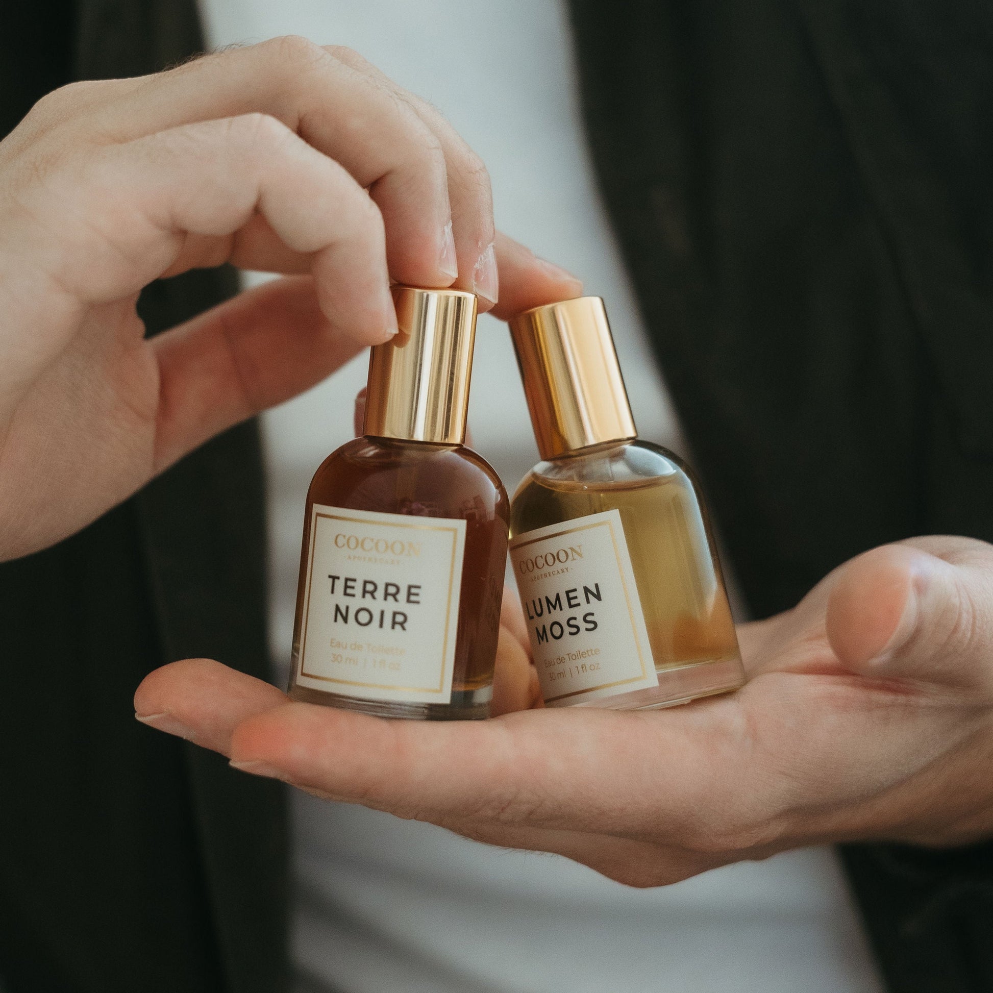 Two small perfume bottles labeled 'Terre Noir' and 'Men's Boss' held in a hand.