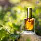Perfume bottle on a rock with greenery in the background